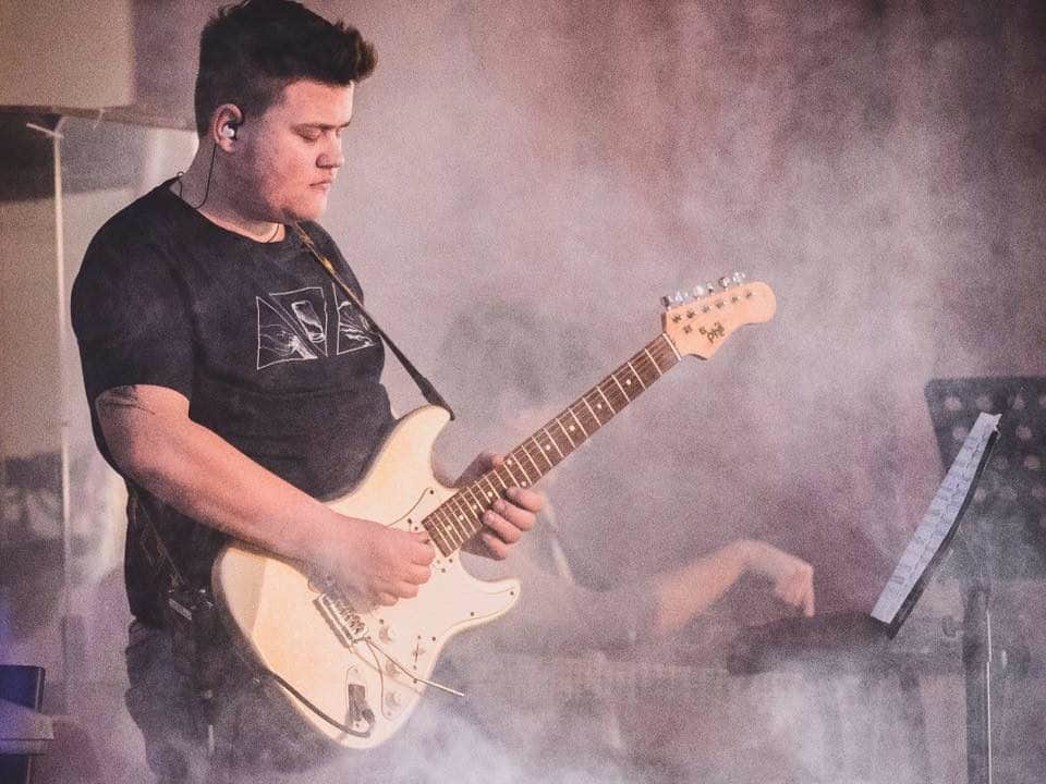 Junger Mann als Gitarrist auf Bühne
